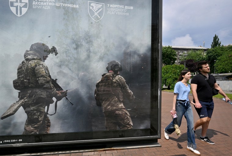 A couple walks past recruiting placard in Ukraine.