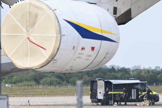 Police forensic technicians prepare to deploy an explosive-disposal robot near an aircraft.