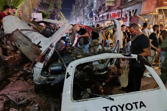 Syrian security personnel inspect damaged vehicles at the site of an explosion in the Jaramana , Syria.