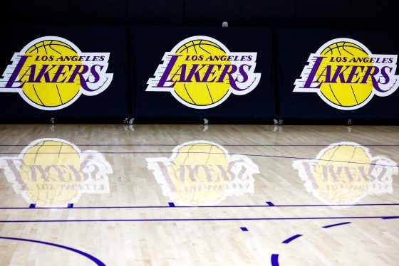 The Los Angeles Lakers logo, printed three times on the wall, appears on the basketball court with reflections on the floor