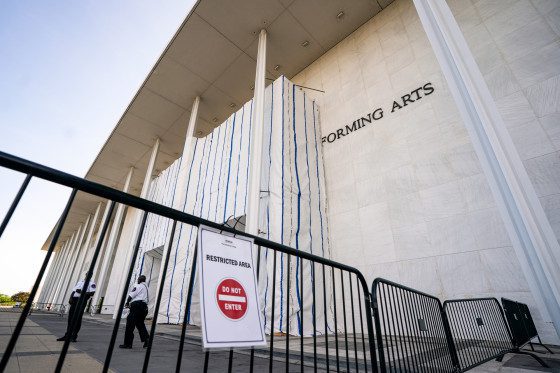 The John F. Kennedy Center for the Performing Arts exterior, tarp covers the front, and a gate can be seen blocking off entry, a sign is on the gate that reads "restricted area, and a Do Not Enter logo"
