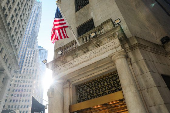 The New York Stock Exchange building exterior, an American flag is posted atop