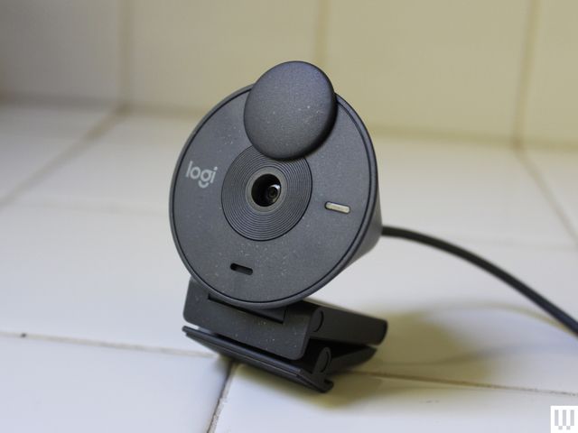 Black circular-shaped webcam with cord sitting on white counter