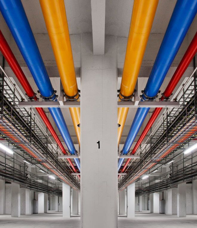 Industrial interior hallway with yellow blue and red pipes lining the ceiling