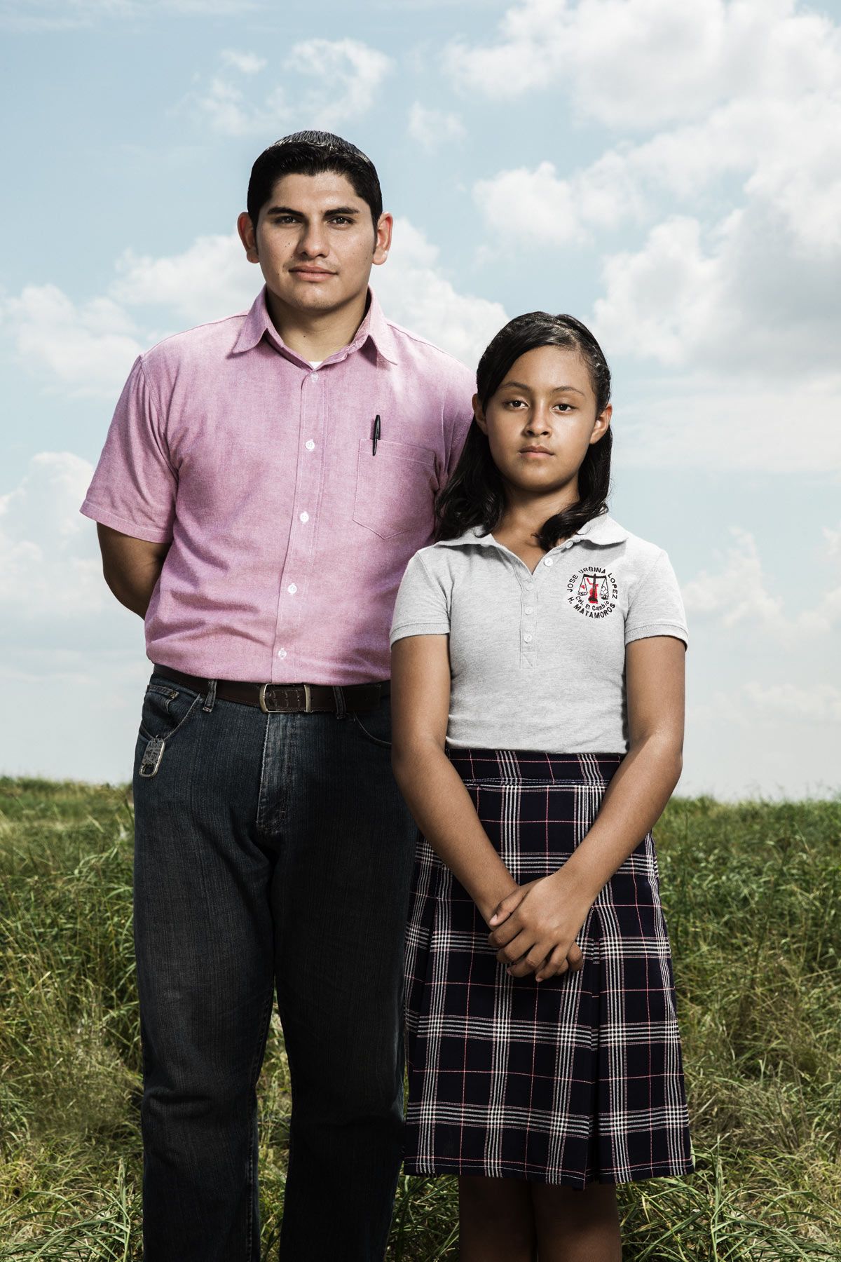 Male teacher stands beside young female student wearing school uniform