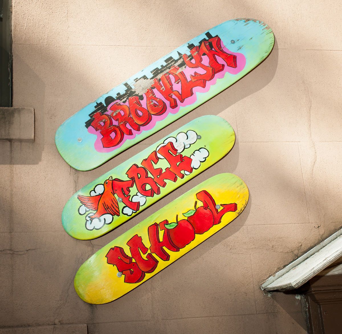 three skate decks with the words Brooklyn Free School