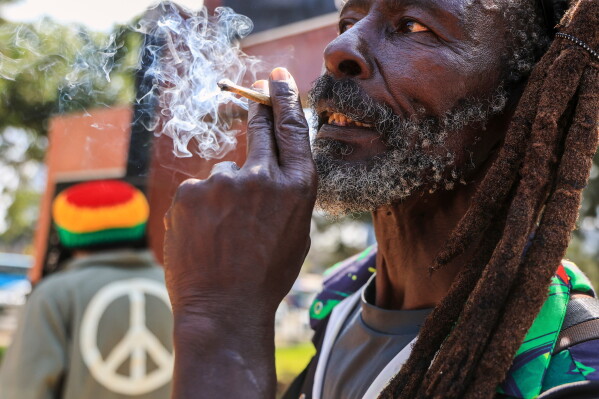 A Rastafarian smokes as they gather outside Milimani Law Courts, after the high court dismisses a Rastafarian case seeking to legalize marijuana, in Nairobi, Wednesday, July 15, 2026. (AP Photo/Andrew Kasuku)