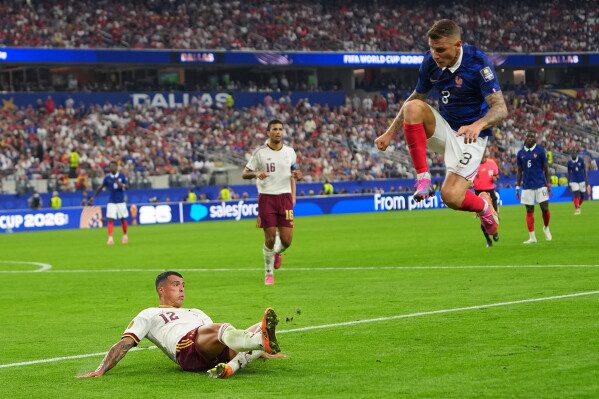 France's Lucas Digne jumps as Spain's Pedro Porro clears the ball during a World Cup semifinal soccer match in Arlington, Texas, near Dallas, Tuesday, July 14, 2026. (AP Photo/Julio Cortez)