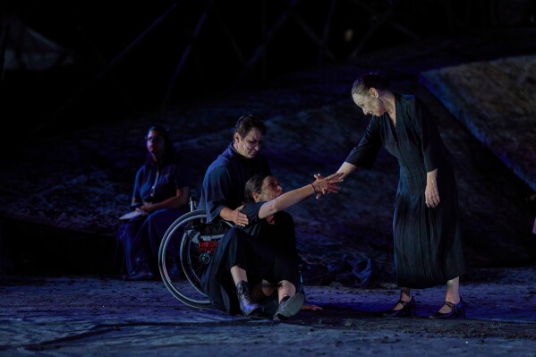 From left to right, Eirini Kourouvani, a wheelchair dancer, Evi Saoulidou and Lydia Fotopoulou perform during a dress rehearsal of Euripides' tragedy The Trojan Women, staged by the National Theatre of Greece, at the Ancient Theater of Epidaurus, Greece, on Thursday, July 30, 2026. (AP Photo/Petros Giannakouris)