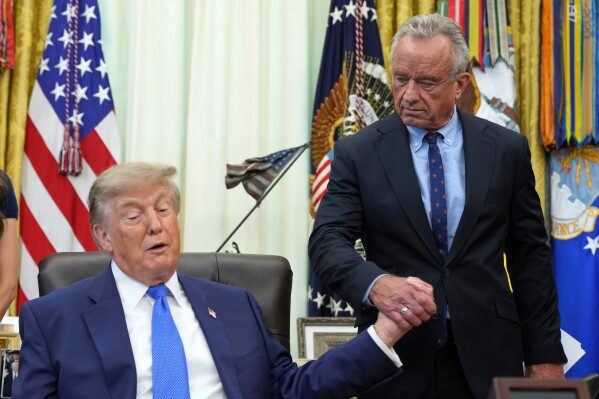 President Donald Trump, left, shakes the hand of Health and Human Services Secretary Robert F. Kennedy Jr. during a meeting to sign an executive order about vaccines, Monday, Aug. 10, 2026, in the Oval Office of the White House in Washington. (AP Photo/Jacquelyn Martin)