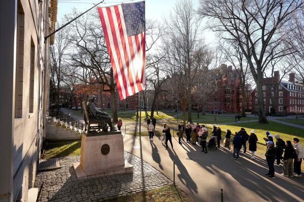 People take photos near a John Harvard statue, left, on the Harvard University campus, Jan. 2, 2024, in Cambridge, Mass. (AP Photo/Steven Senne, File)