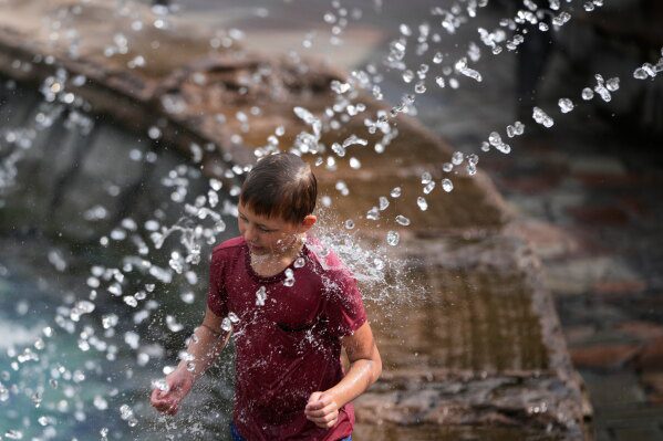 A boy cools himself off in a fountain on a hot summer day in Moscow, Thursday, Aug. 6, 2026. (AP Photo/Pavel Bednyakov)
